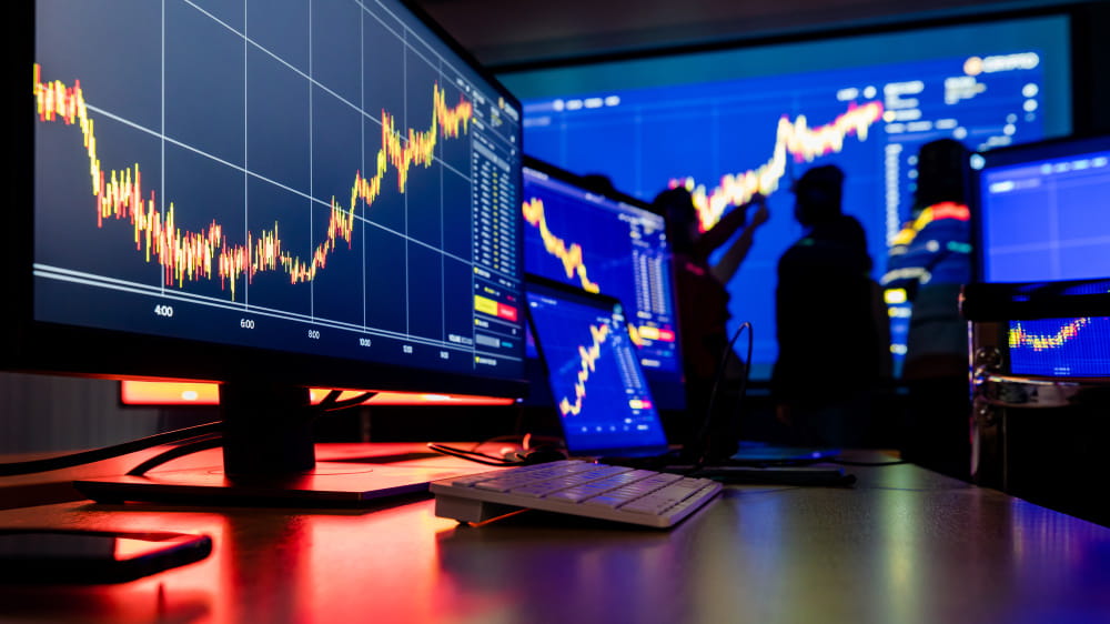 Graphiques boursiers dynamiques sur plusieurs moniteurs illustrant la gestion du risque en trading en temps réel