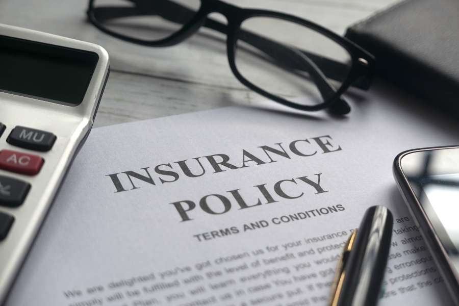 Un document "POLITIQUE D'ASSURANCE" avec des lunettes, une calculatrice et un stylo sur un bureau en bois.